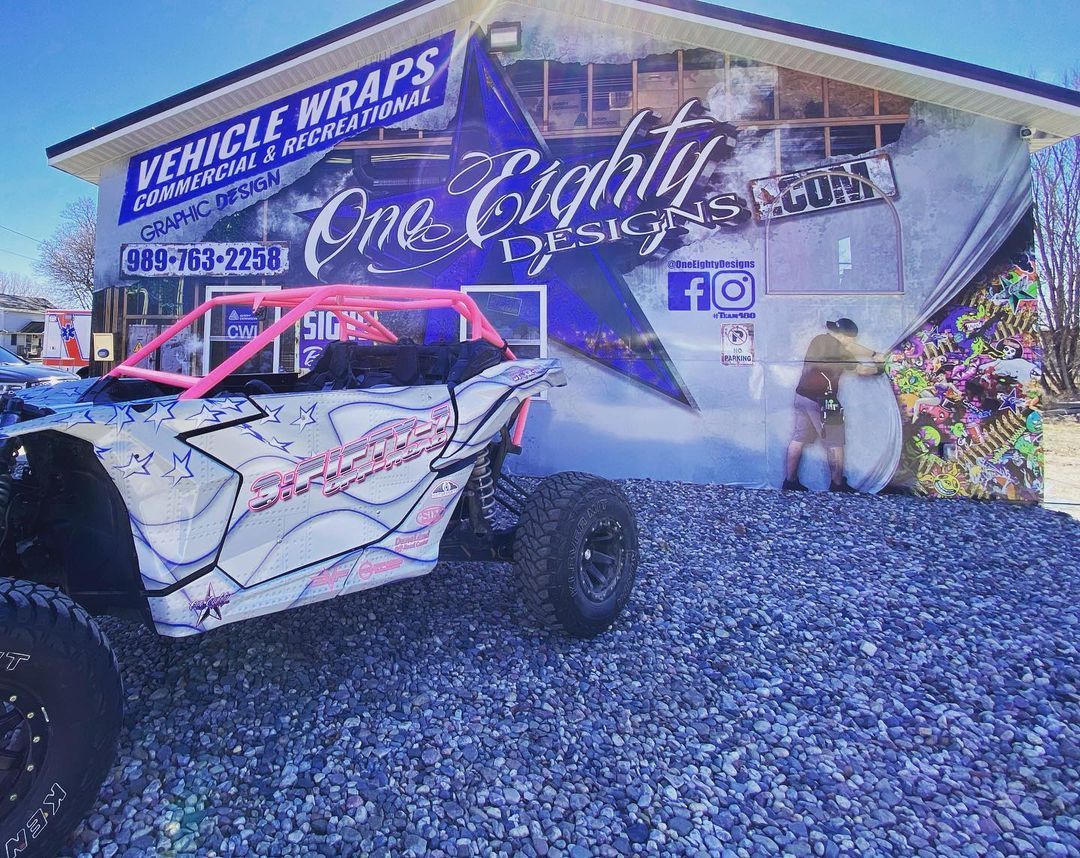 A vehicle is parked in front of a building that says vehicle wraps.