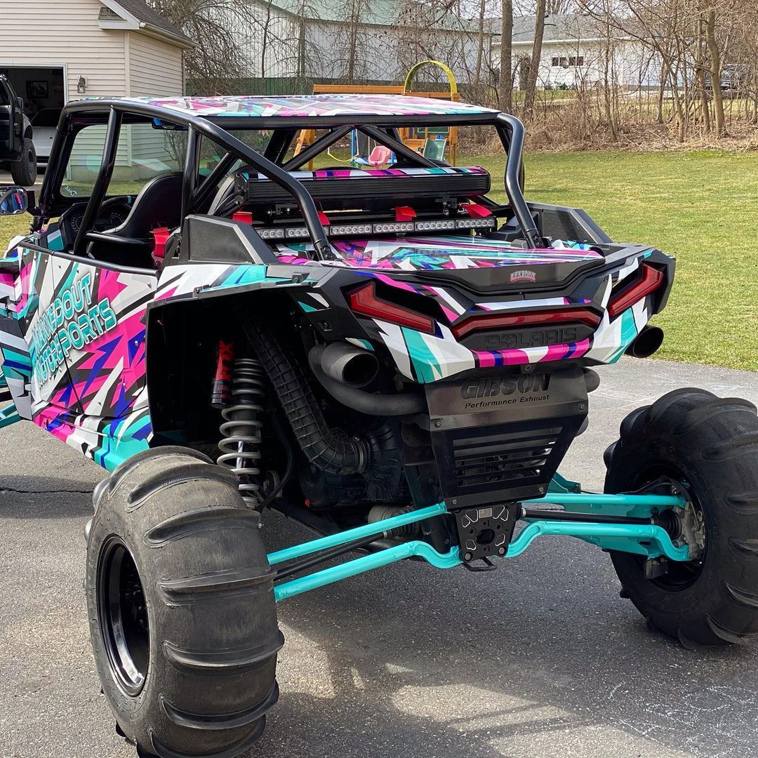 A colorful atv is parked in a driveway next to a house.