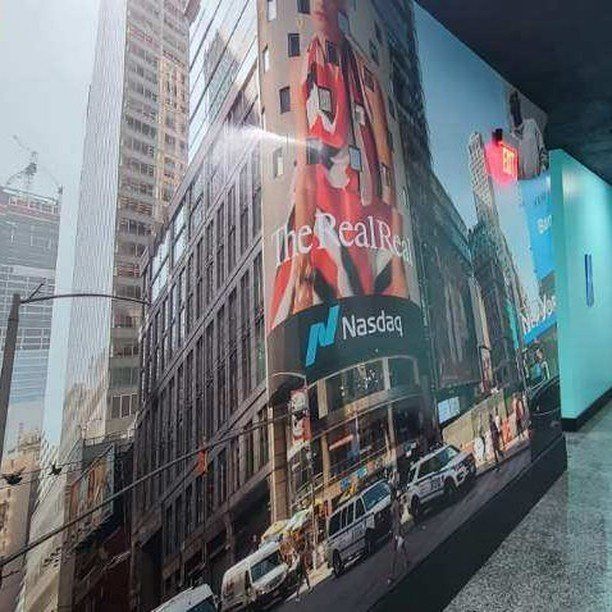 A wall with a picture of a city and a nasdaq sign