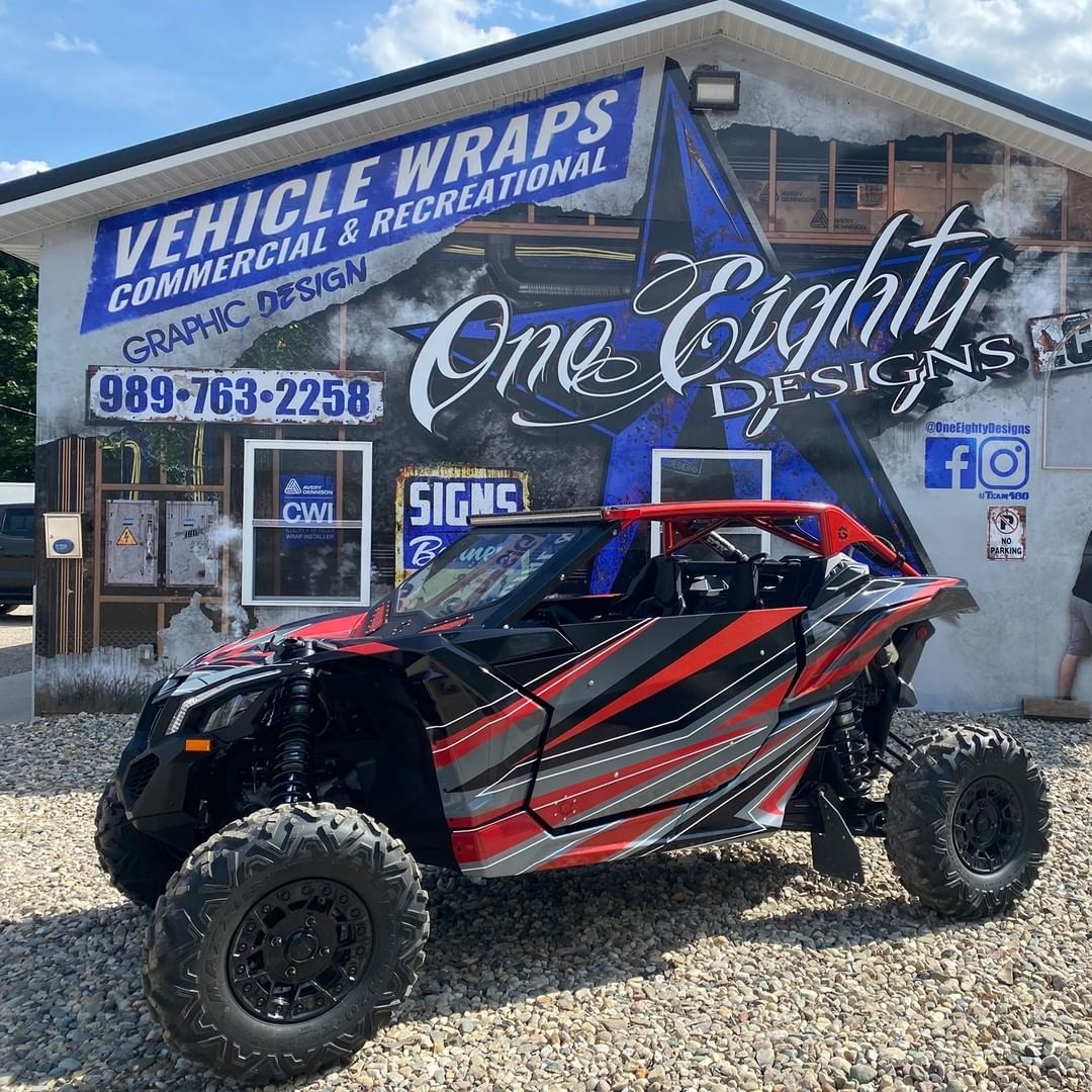 A red and black atv is parked in front of a building.