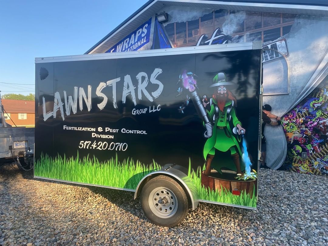 A lawn stars trailer is parked in a gravel lot.