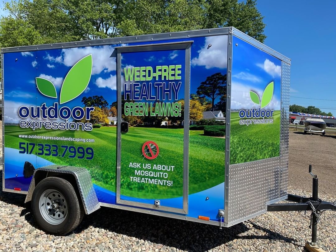 A trailer with a weed free healthy green lawn advertisement on it.