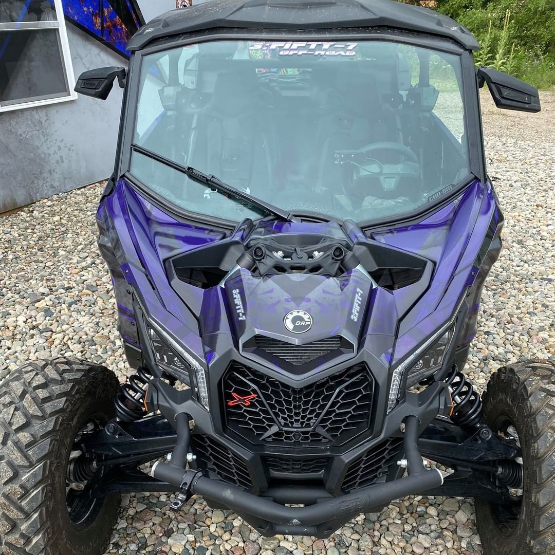 A purple atv is parked on a gravel road.