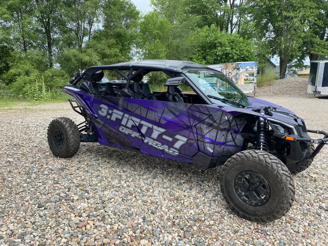 A purple atv is parked on a gravel road.