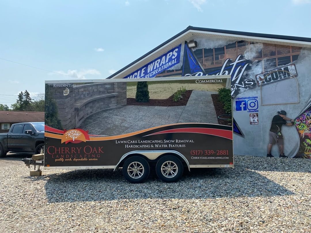 A trailer is parked in front of a building on gravel.