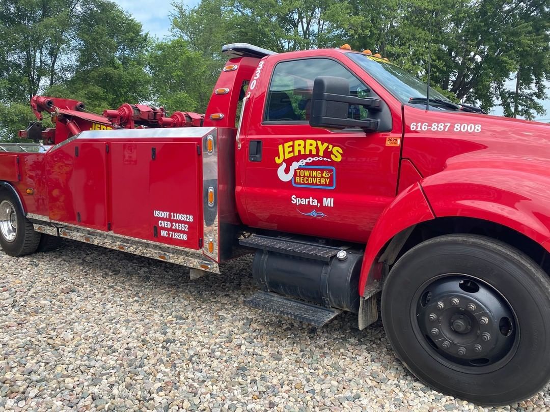 A red tow truck is parked on a gravel road.