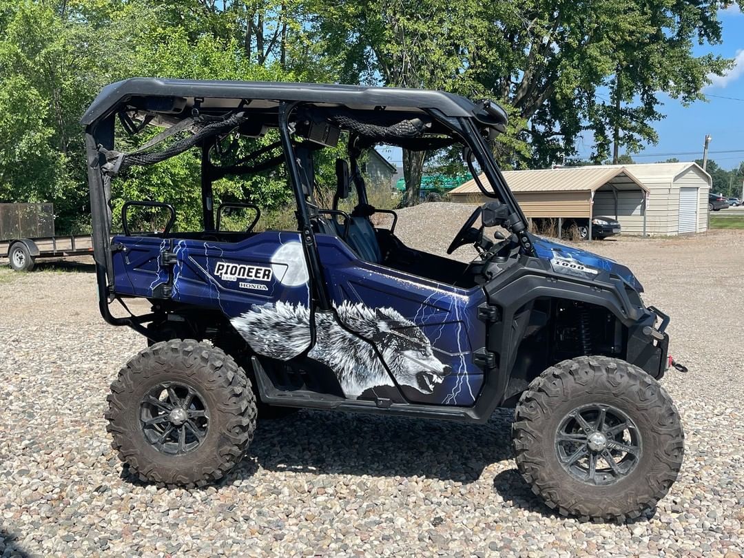 A blue and black atv is parked in a gravel lot.