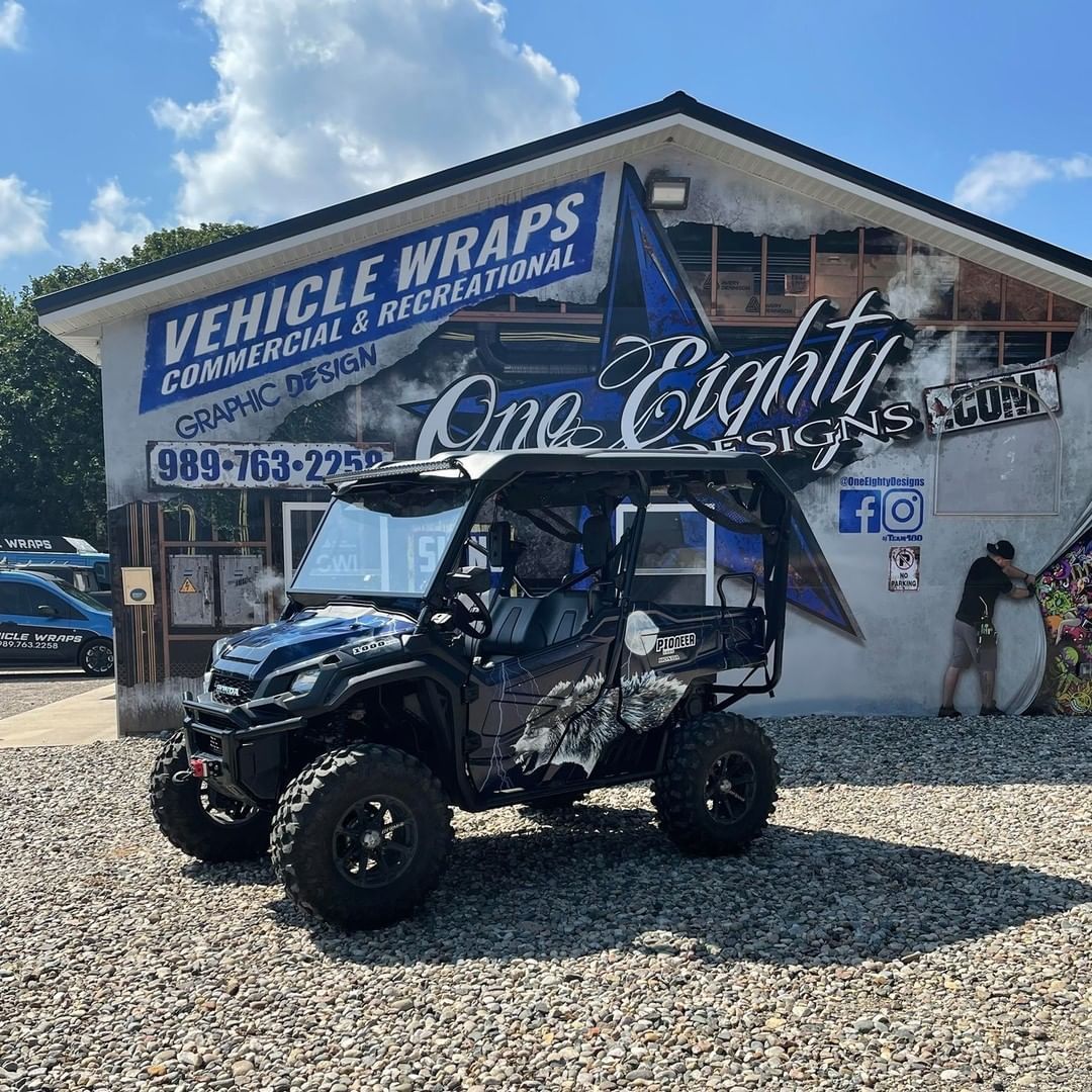 A vehicle is parked in front of a building that says vehicle wraps.