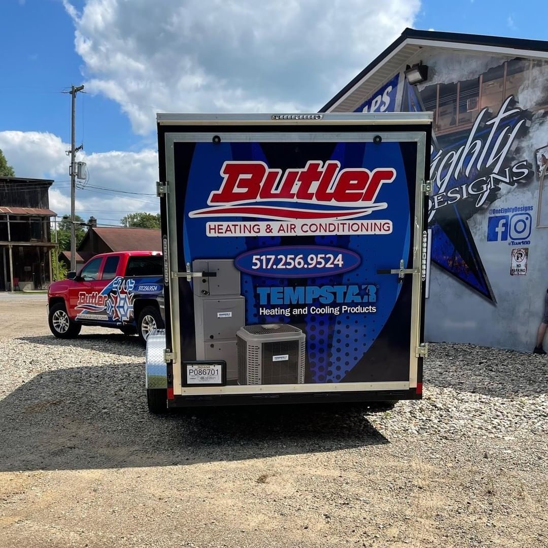 A butler trailer is parked in front of a building