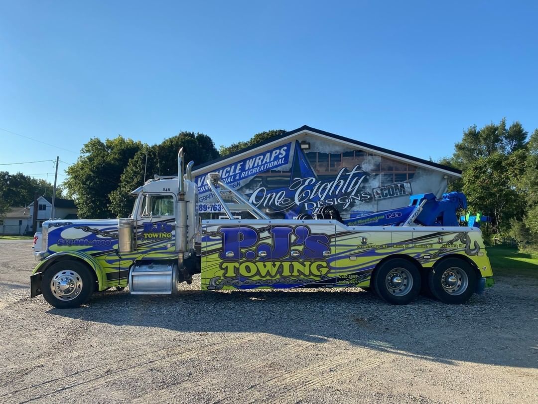 A large tow truck is parked in front of a building.