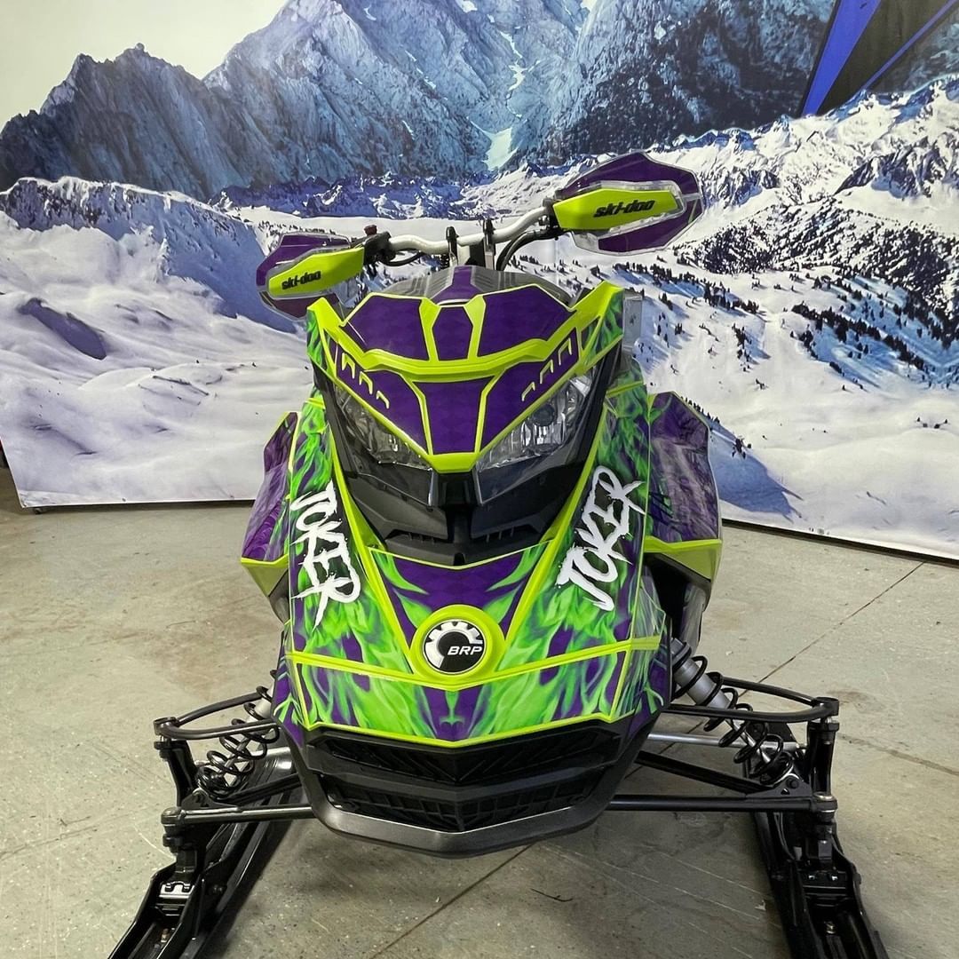 A green and purple snowmobile with the word joker on the front