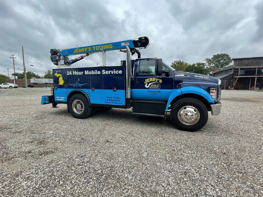 A blue and black truck is parked in a gravel lot.