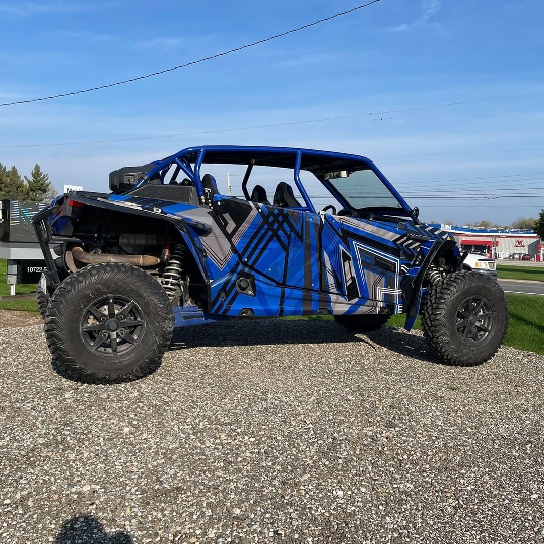 A blue atv is parked on a gravel road.