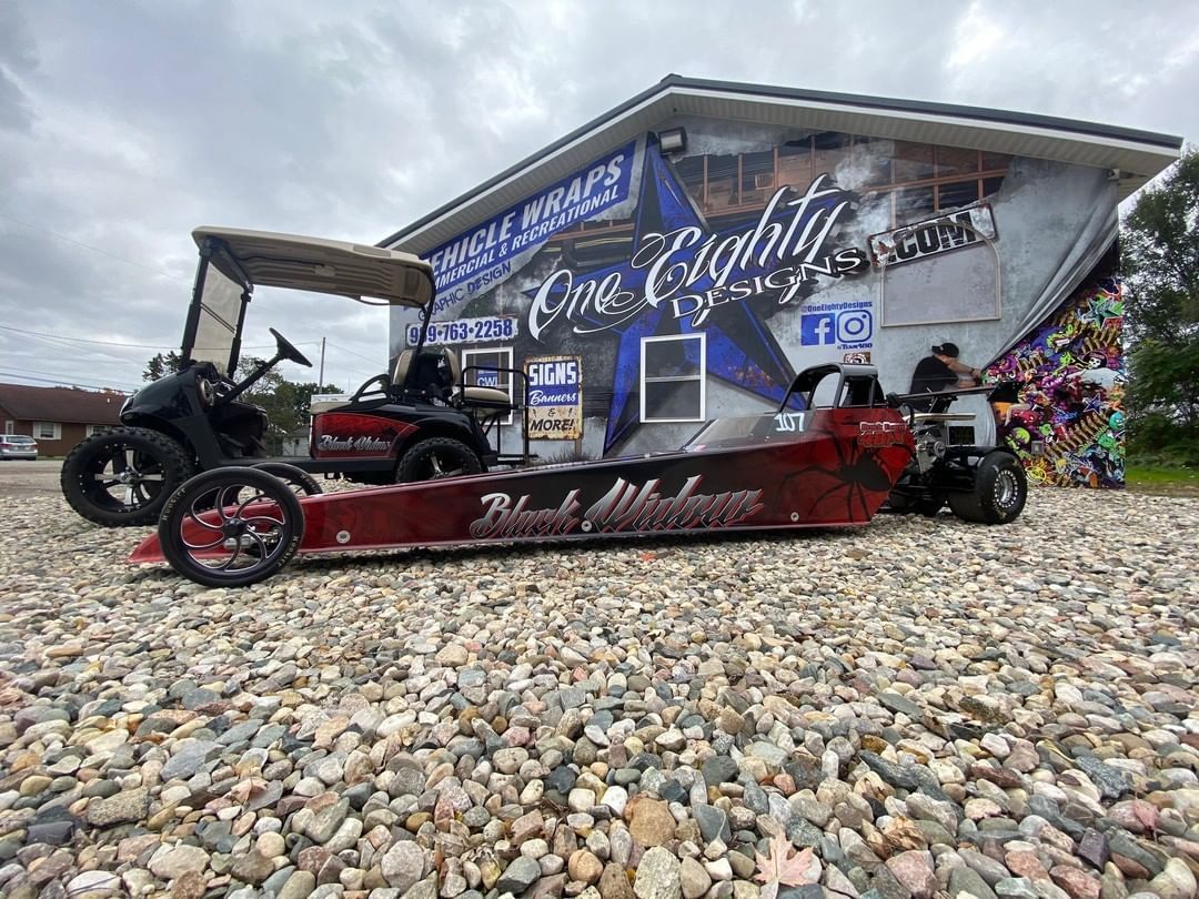 A golf cart is parked in front of a building on a gravel lot.