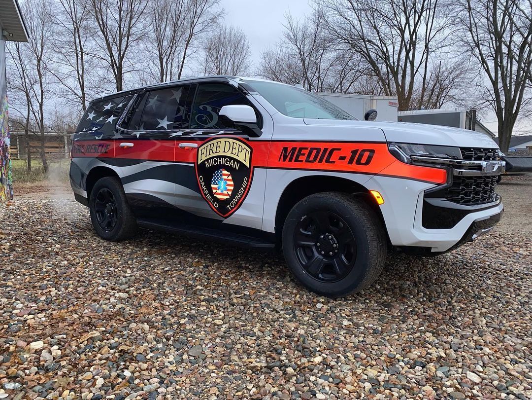 A white and red suv is parked on a gravel road.
