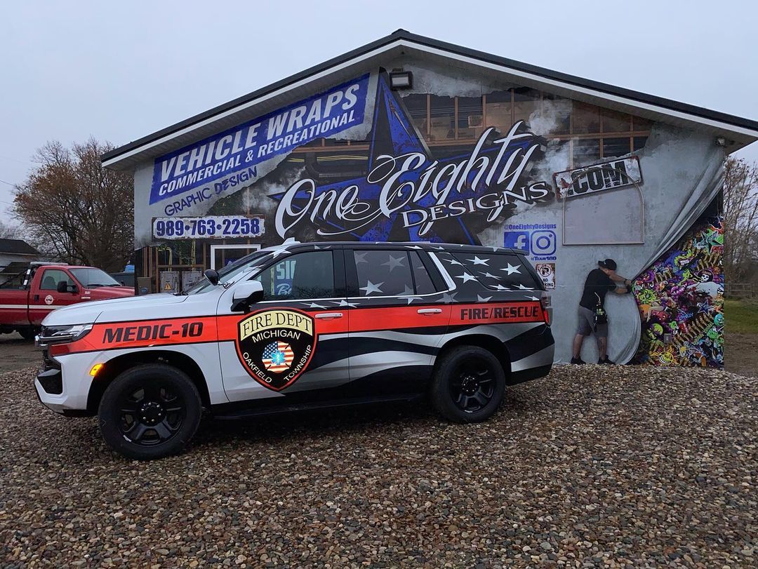A car is parked in front of a building that says vehicle wraps.