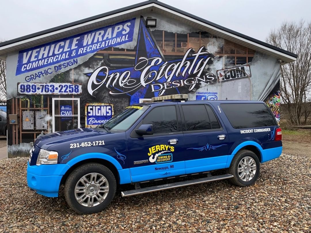 A blue and white suv is parked in front of a building.