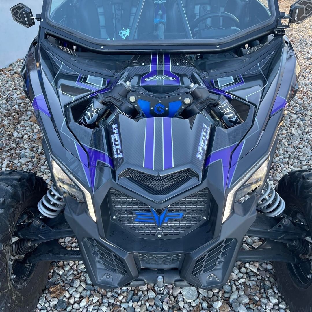 A black and purple atv is parked on gravel.