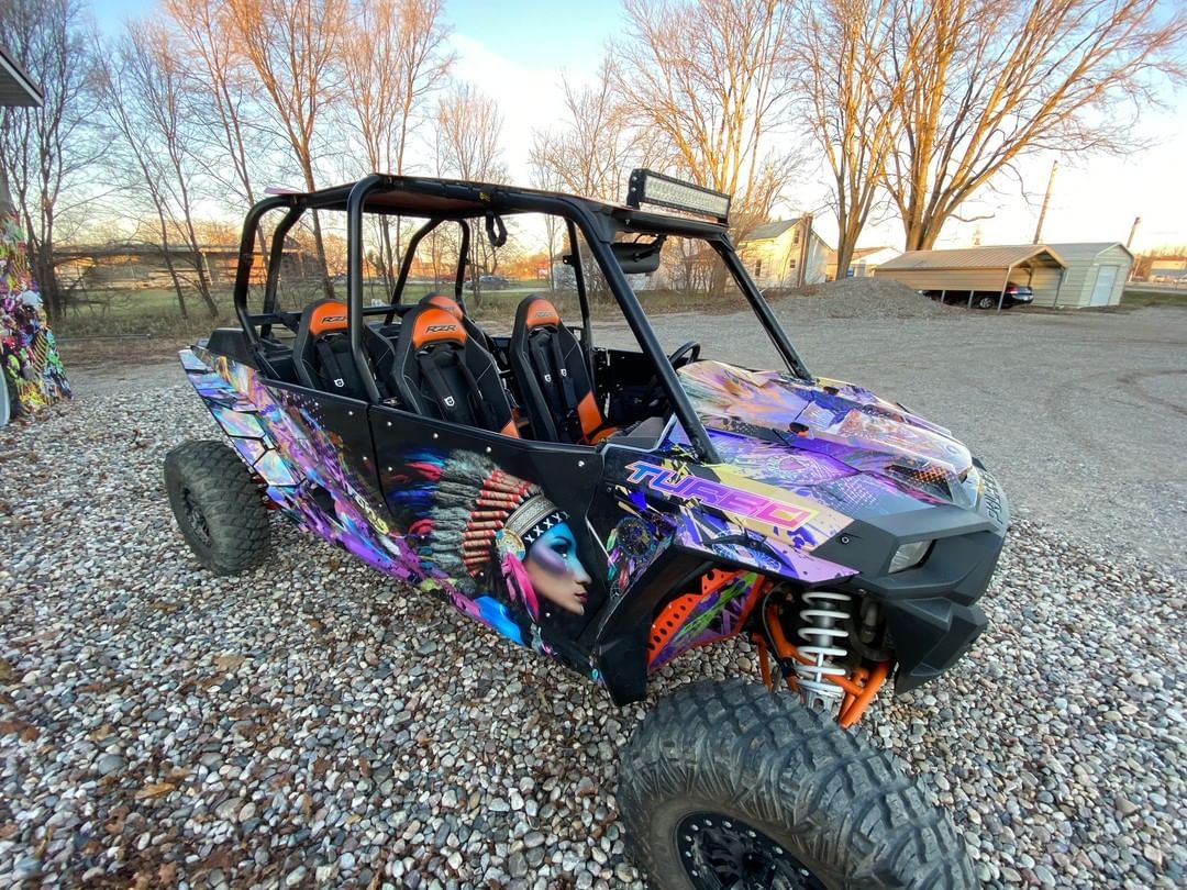 A purple and orange atv is parked in a gravel lot.