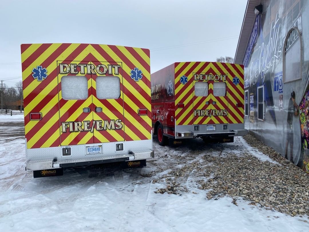 Two fire ems trucks are parked in the snow