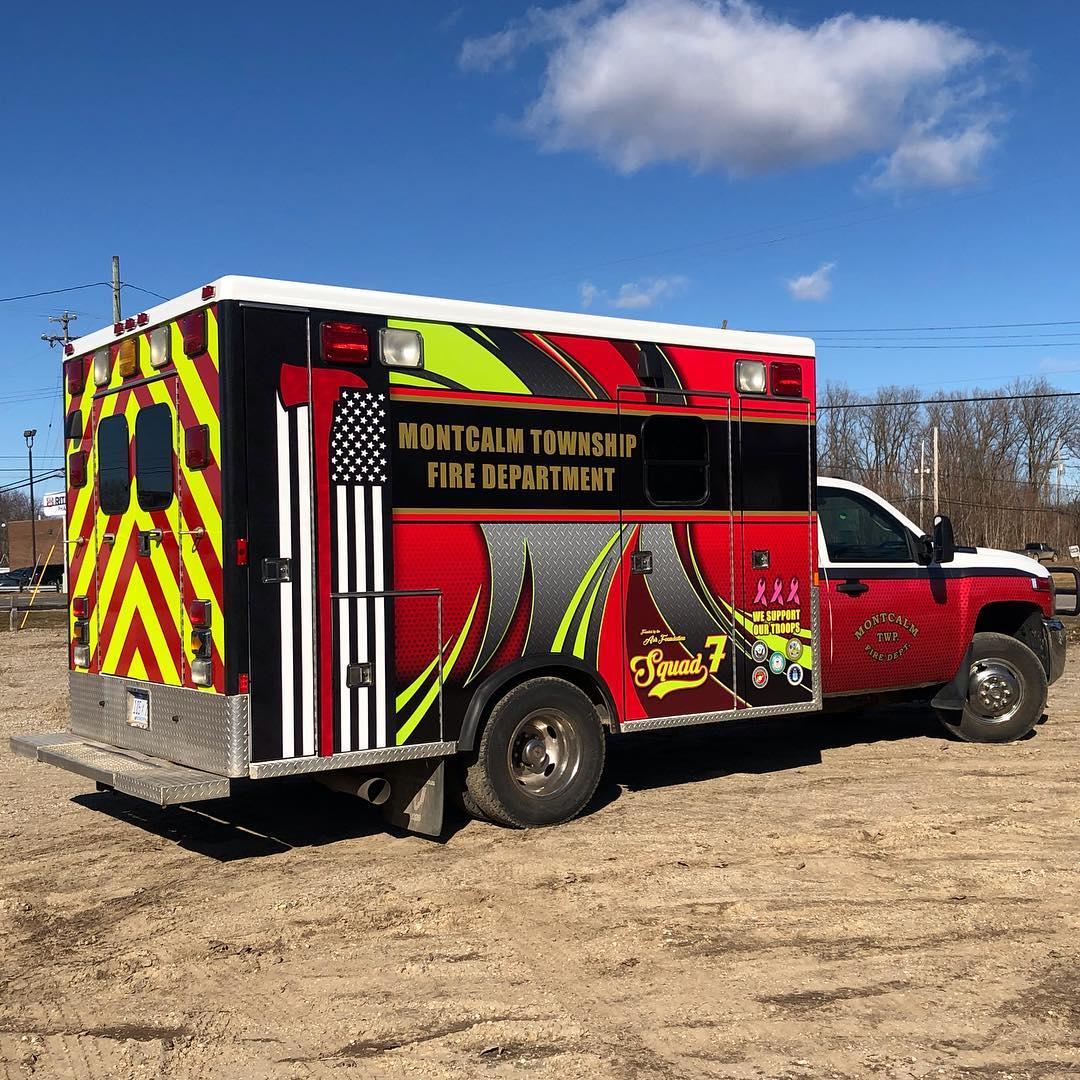 A red fire truck is parked in a dirt field.