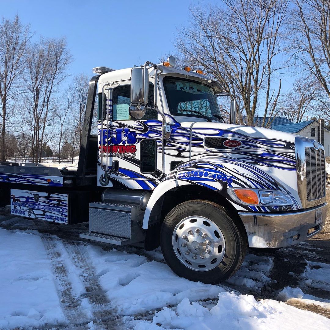 A tow truck is parked in the snow on a snowy road.