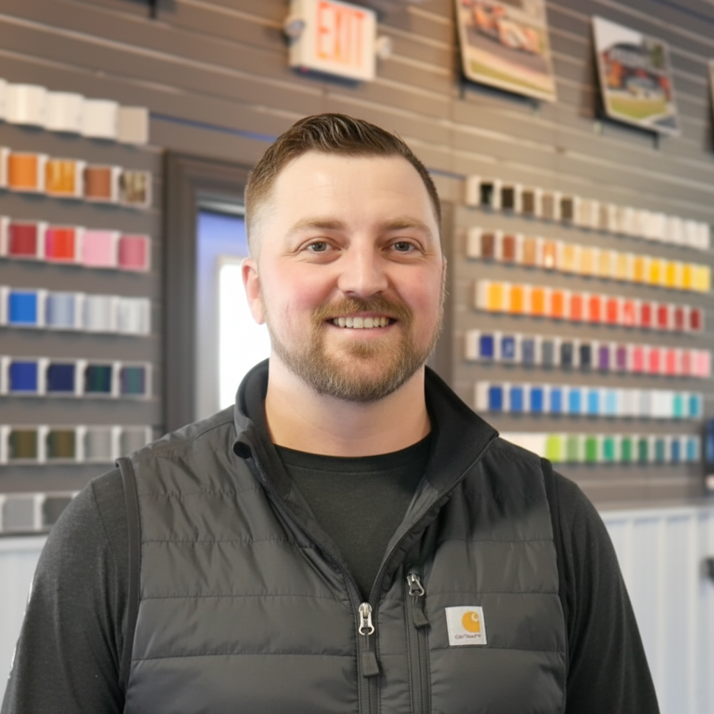 A man in a black vest is standing in front of a wall with a red exit sign on it.