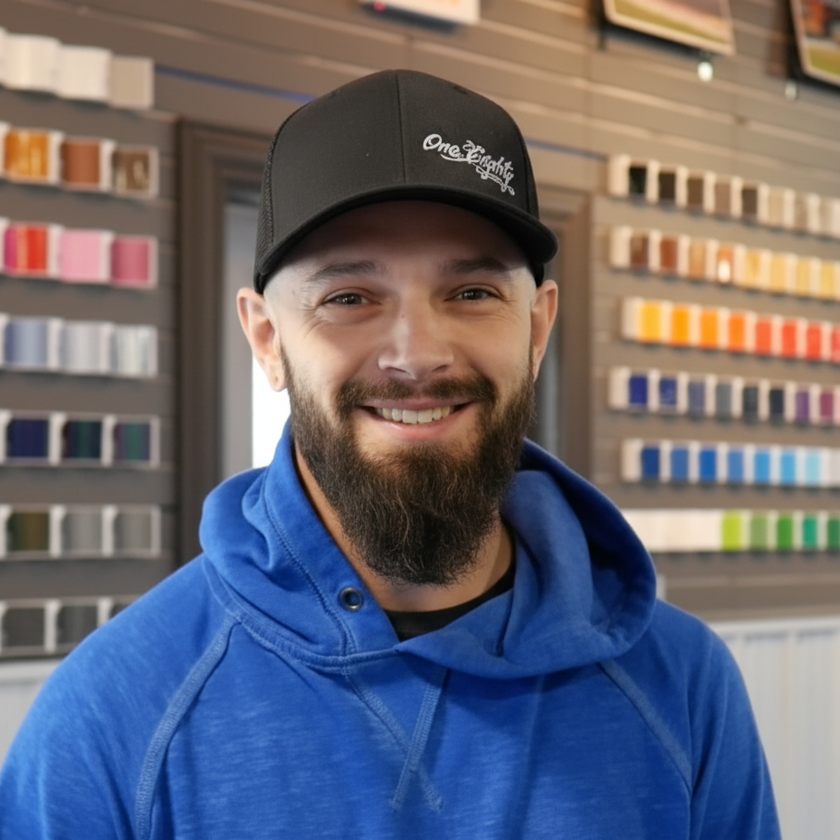 A man with a beard wearing a blue hoodie and a black hat