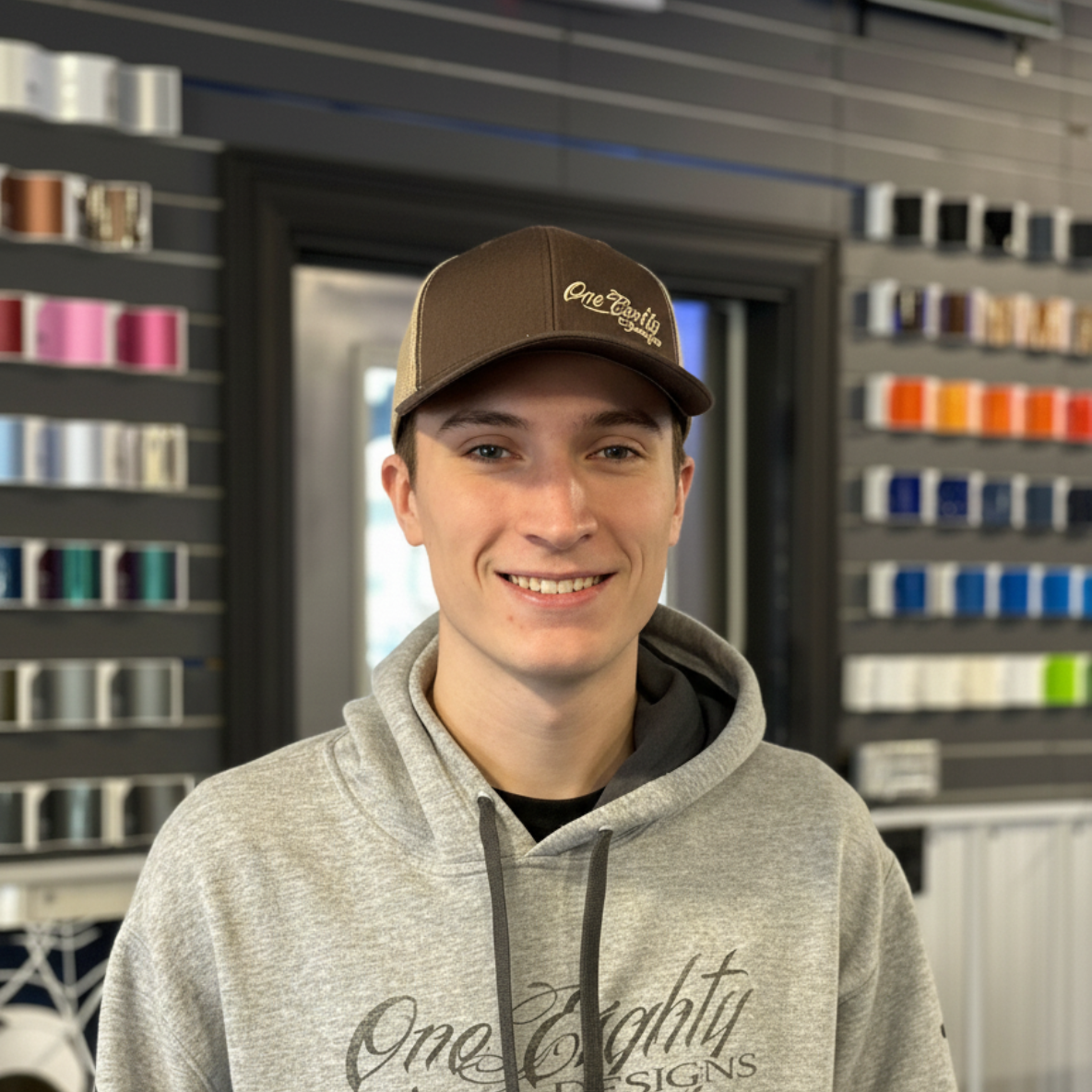 A man wearing a hat and a hoodie with the word one eighty on it