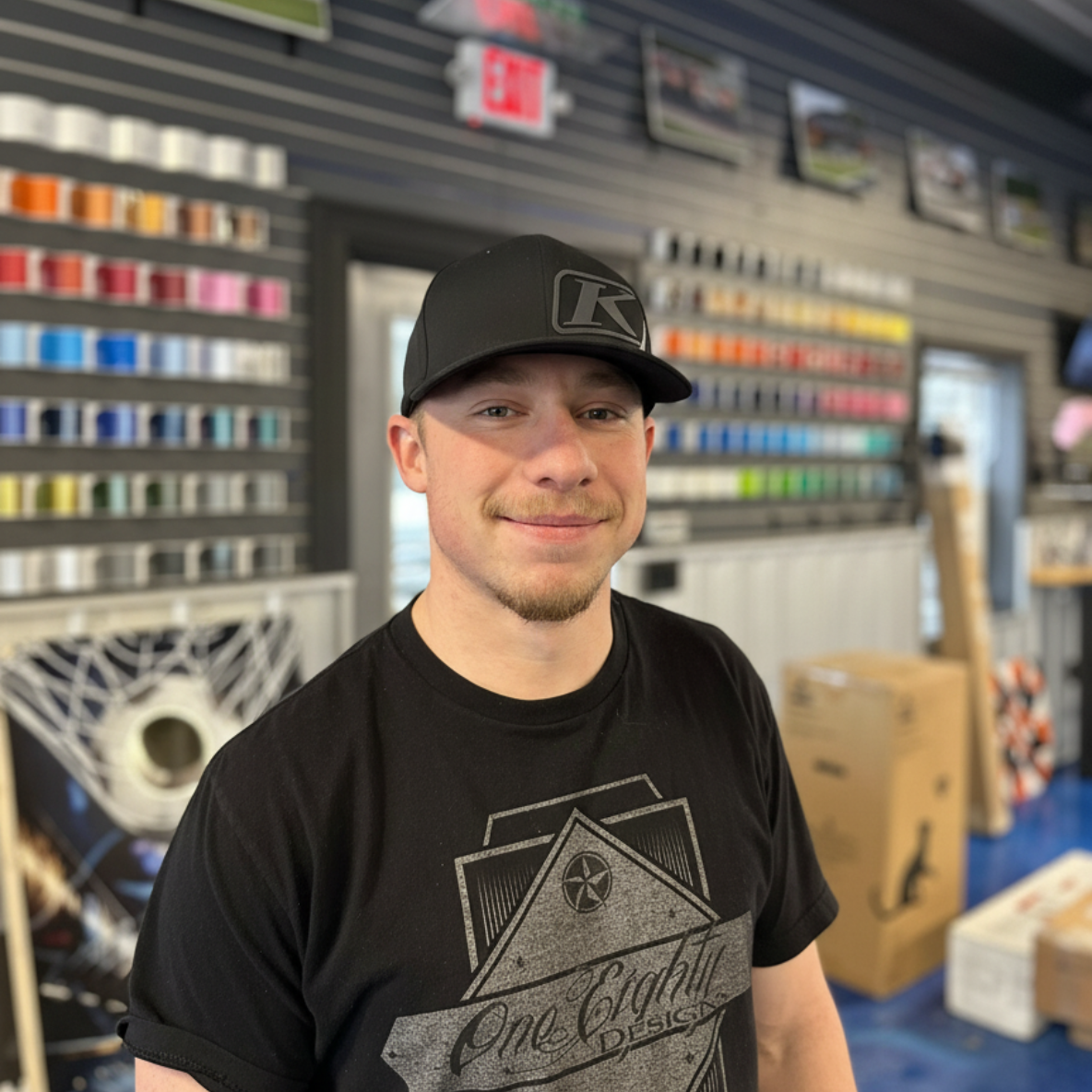 A man wearing a black hat and a black shirt is standing in front of an exit sign