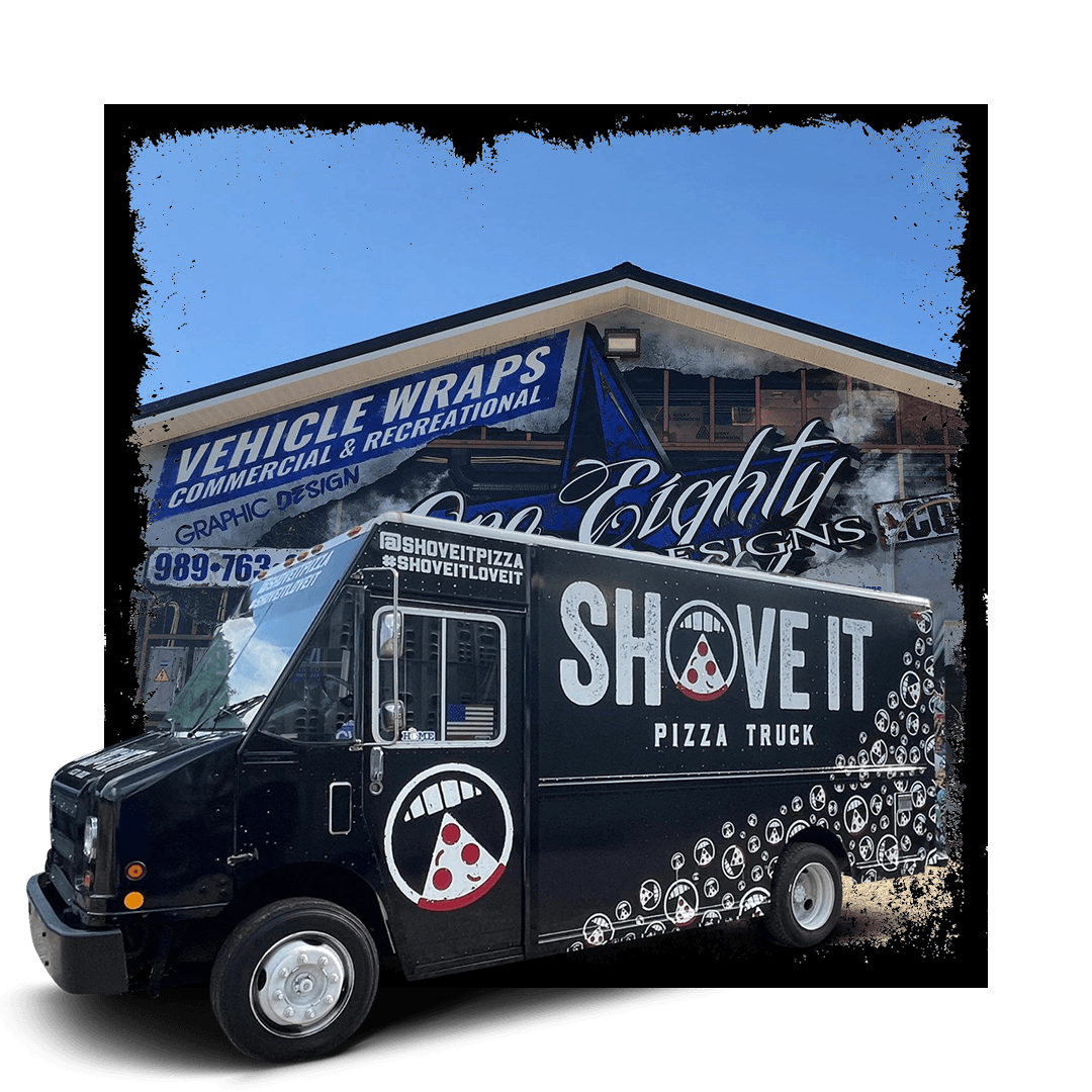 A black pizza truck is parked in front of a building.