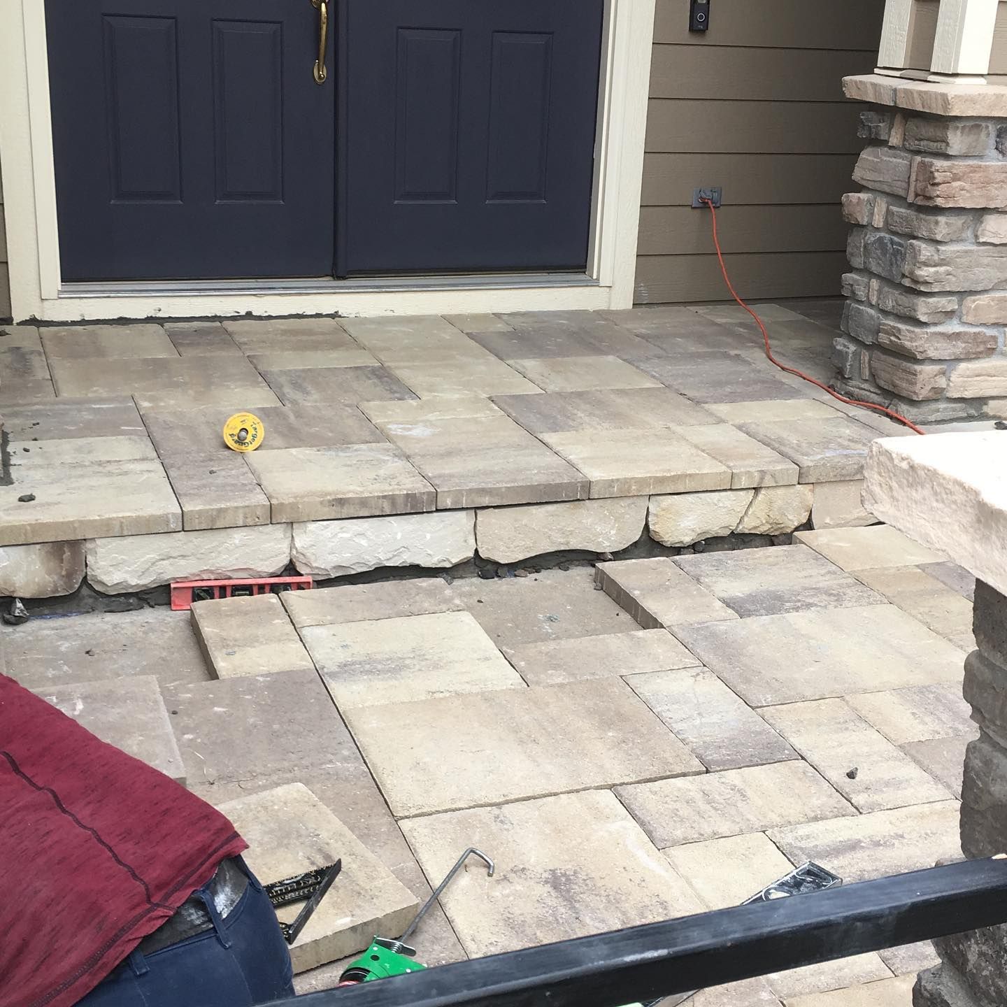 A person is constructing a stone pathway in front of a blue door.