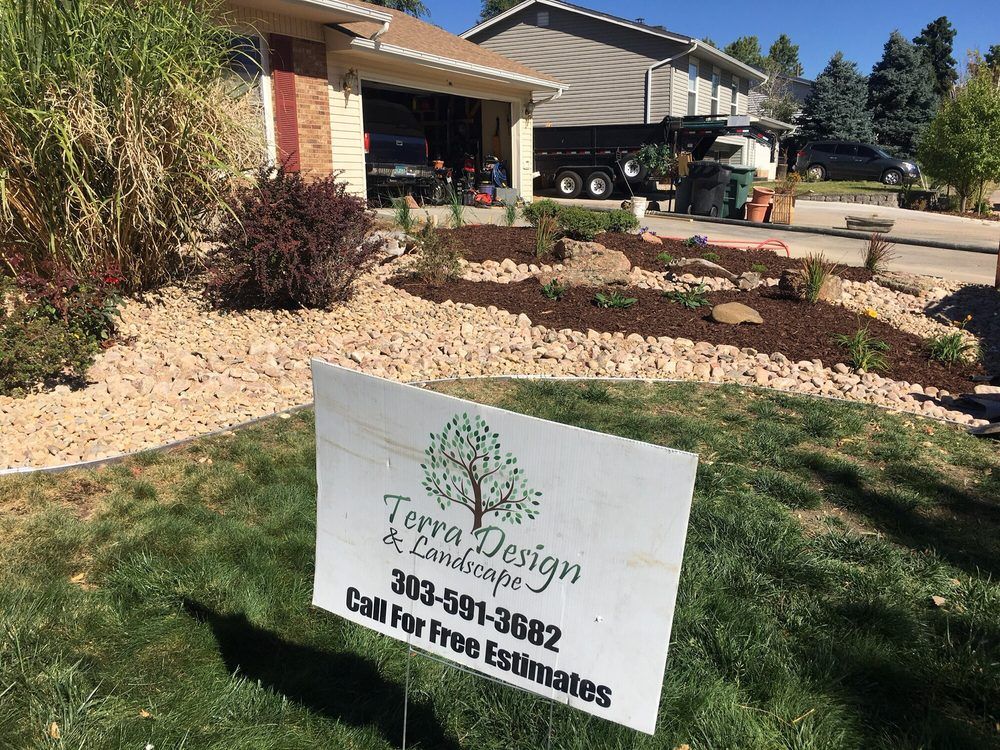A sign in front of a house with landscaping, reading 