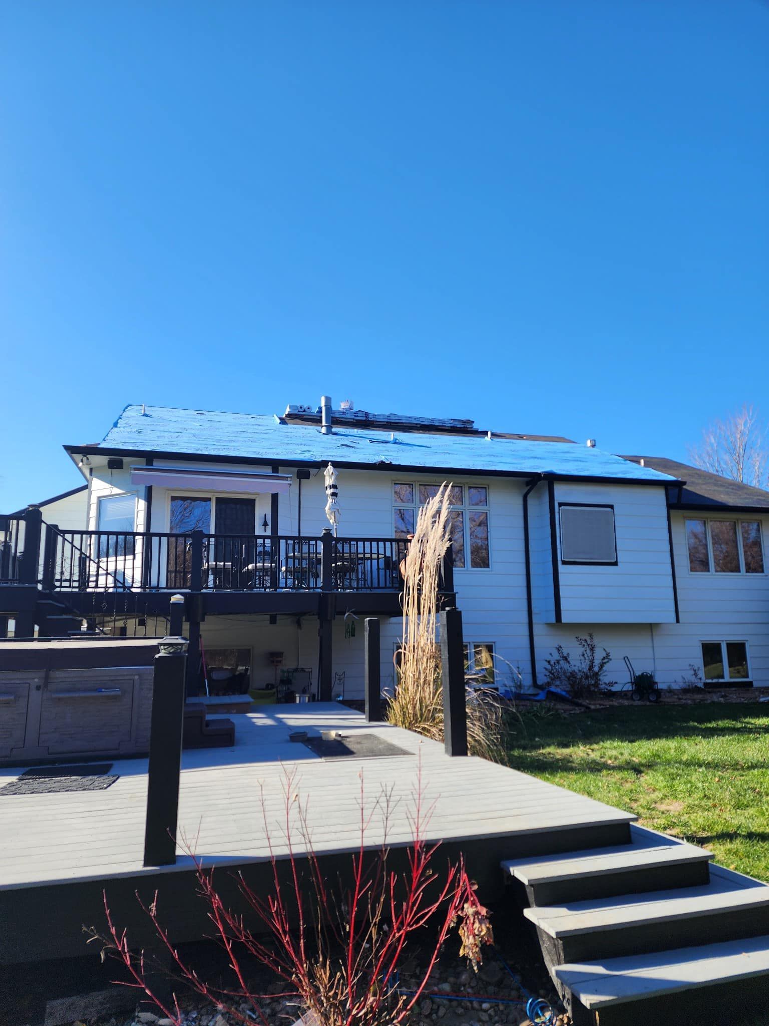 A white house with a blue roof and a deck