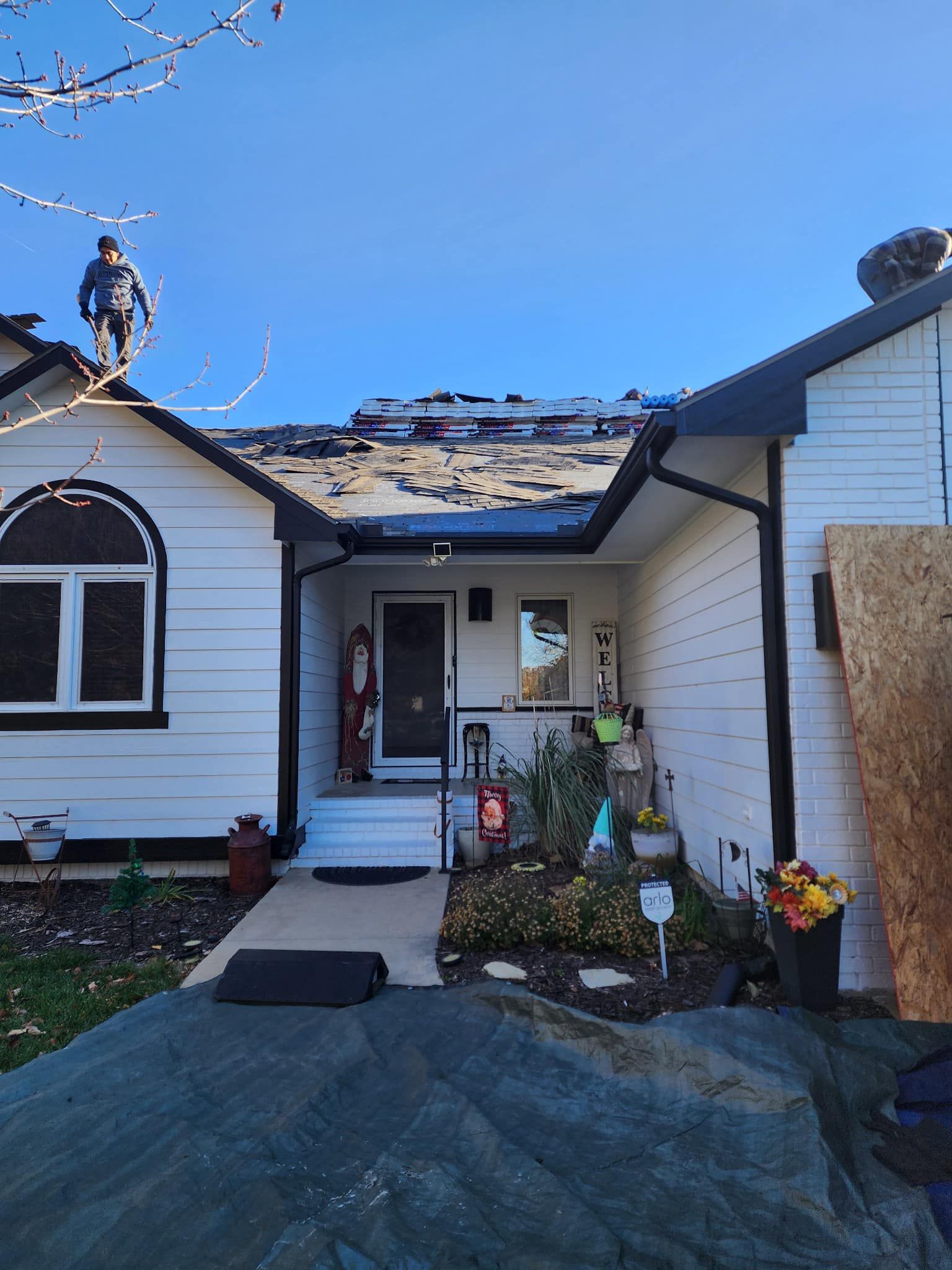 A white house with a roof that has been damaged by a storm.