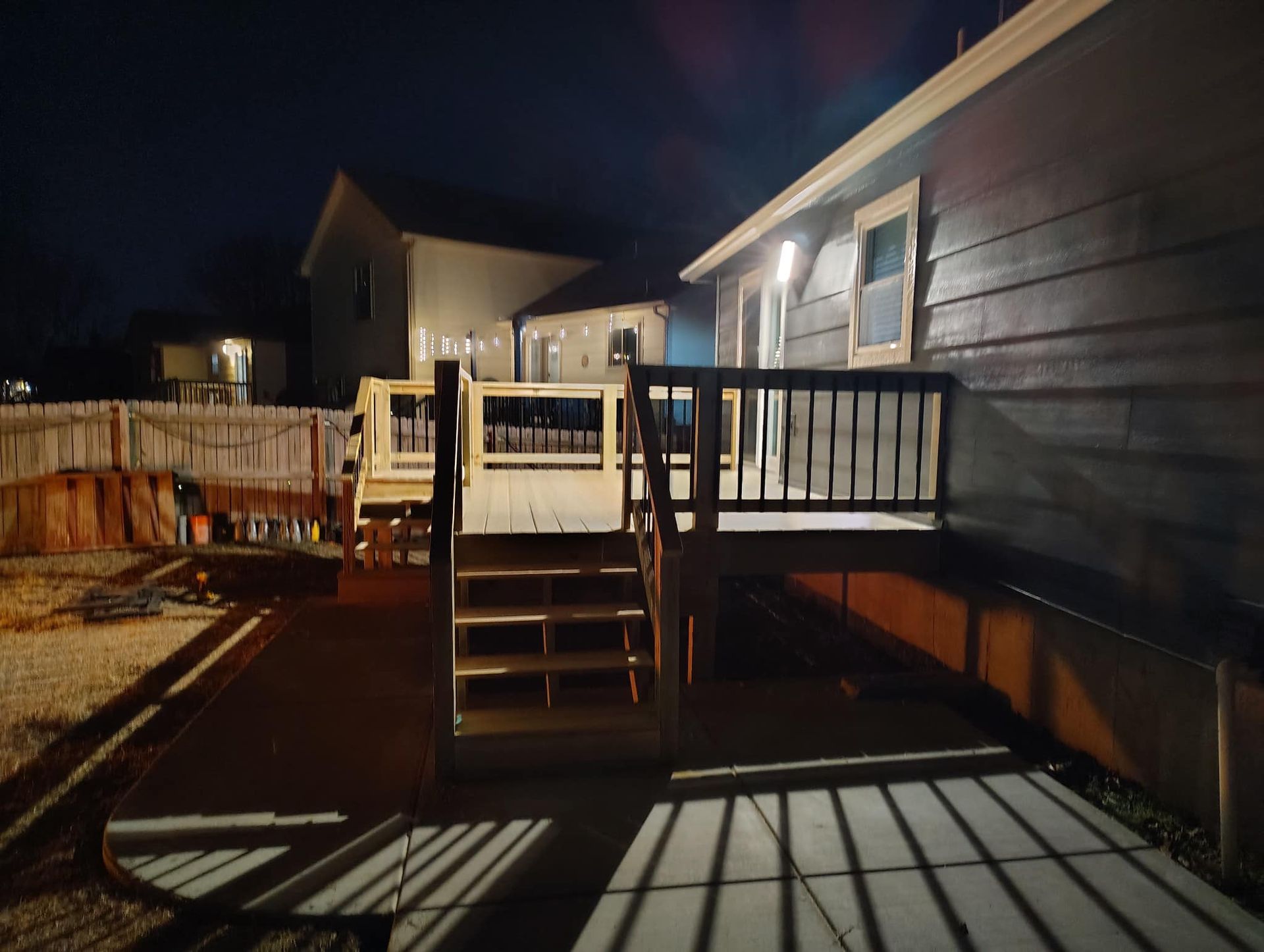 A house with a deck and stairs is lit up at night