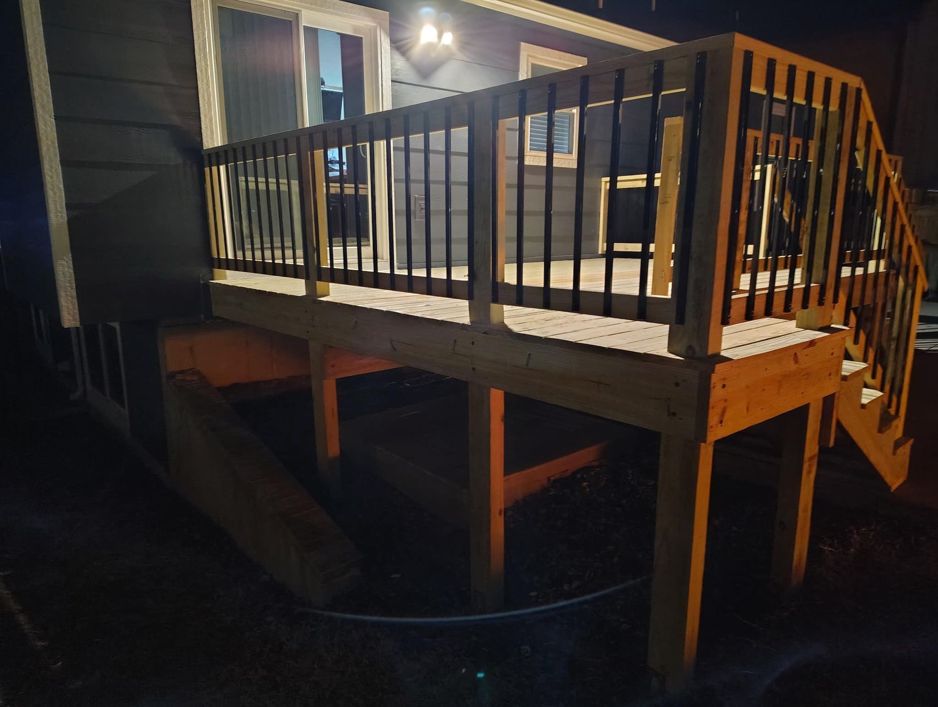A wooden deck with stairs is lit up at night