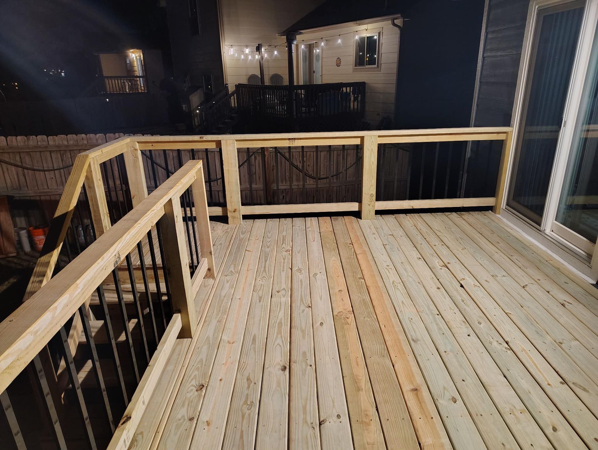 A wooden deck with stairs and a railing at night.