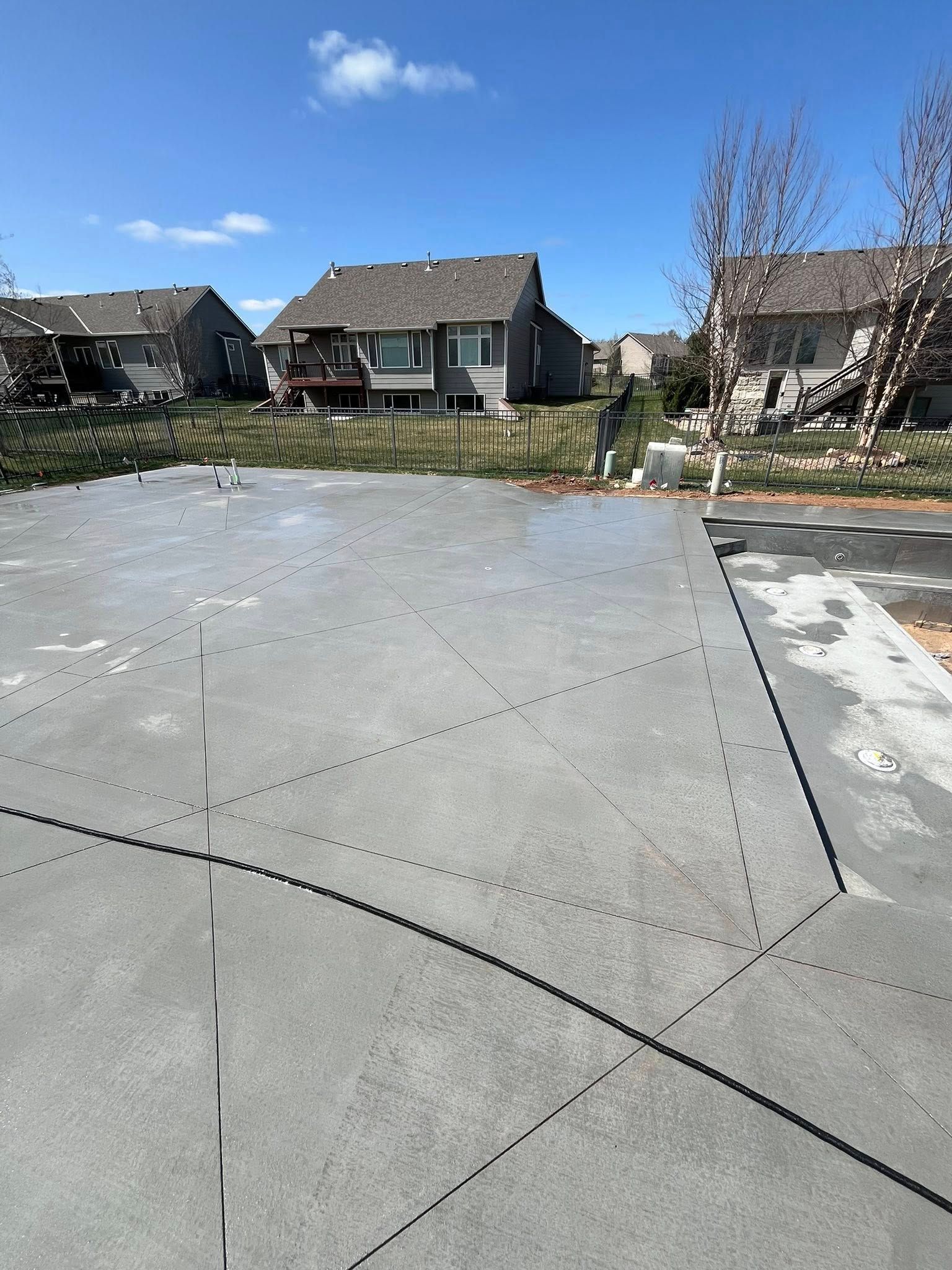 A concrete driveway in a residential area with a house in the background.