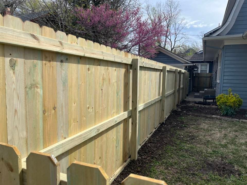 A wooden fence is in the backyard of a house.