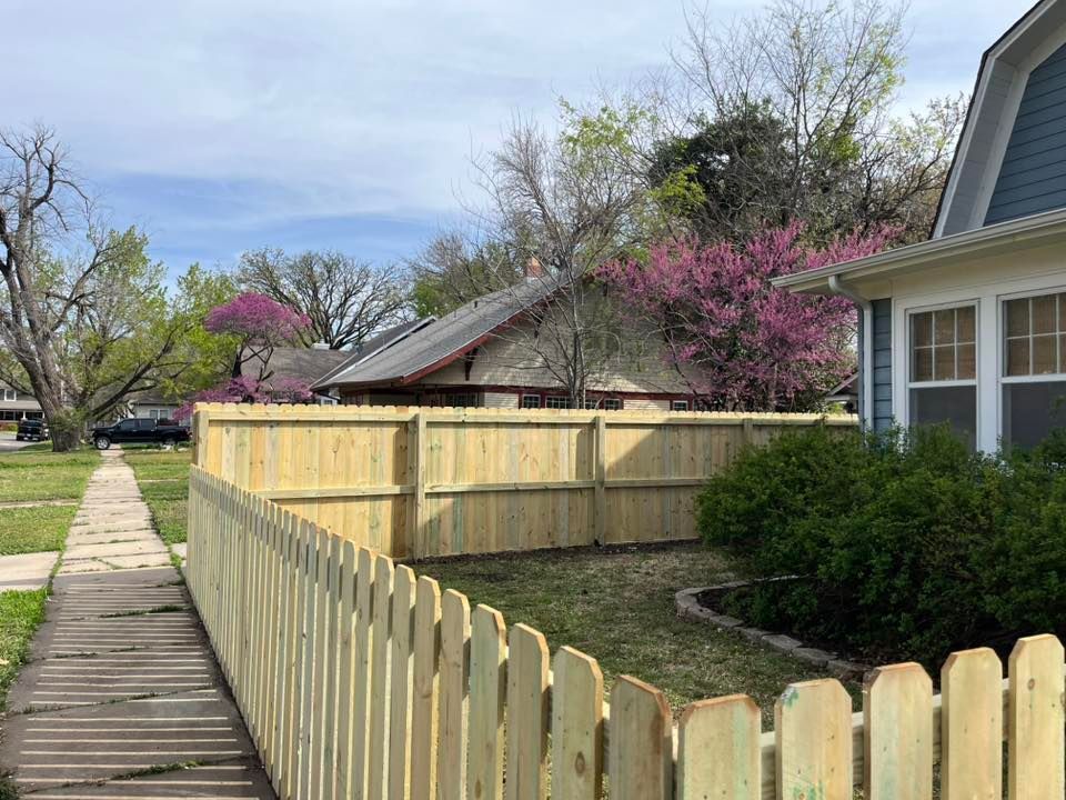 A wooden fence is surrounding a house in a residential area.