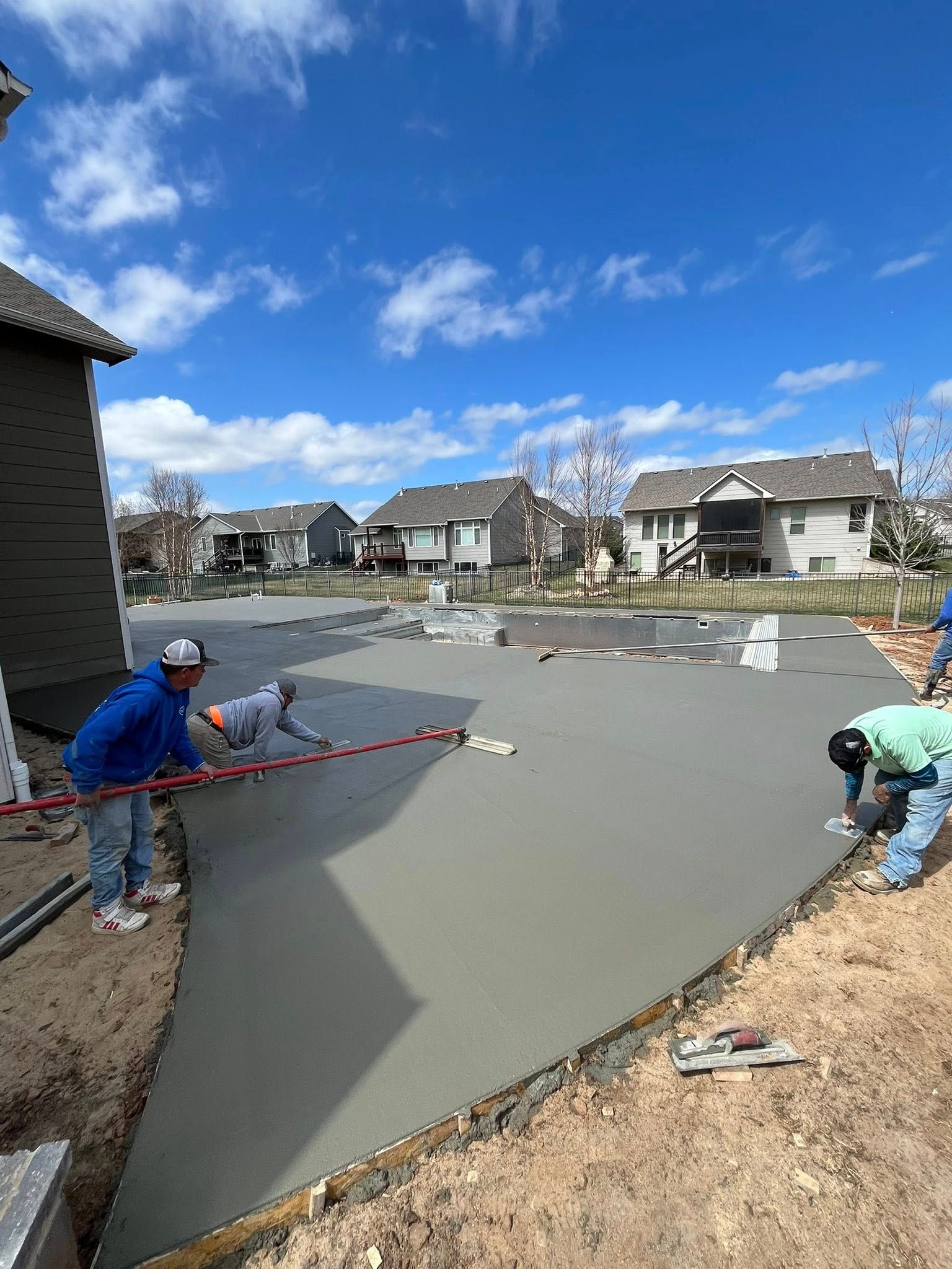 A group of construction workers are working on a concrete driveway.