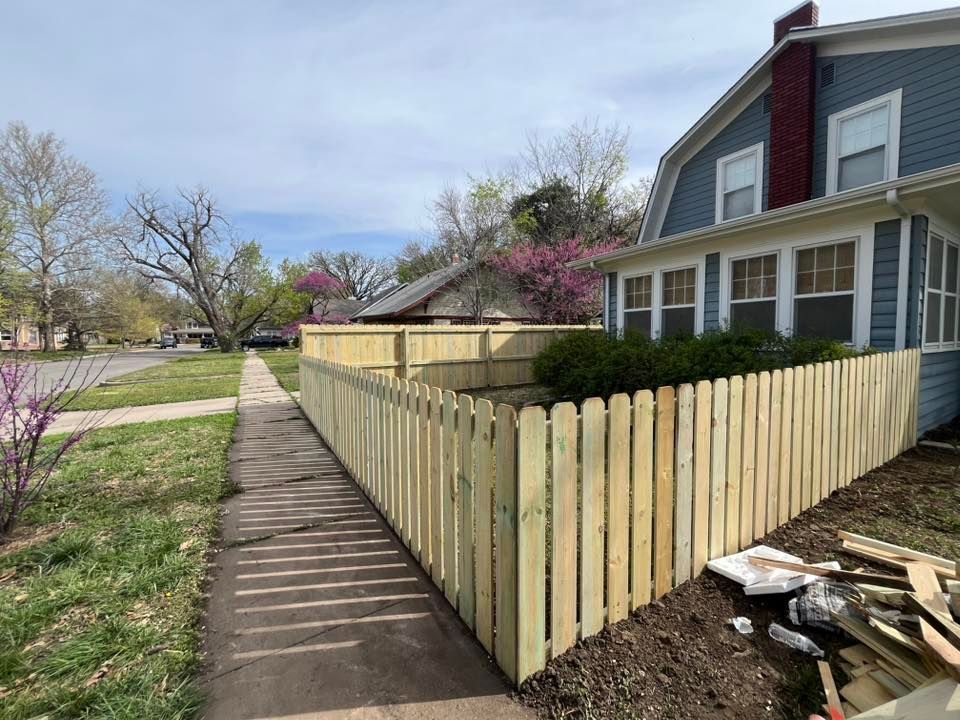 A wooden picket fence is being built in front of a house.