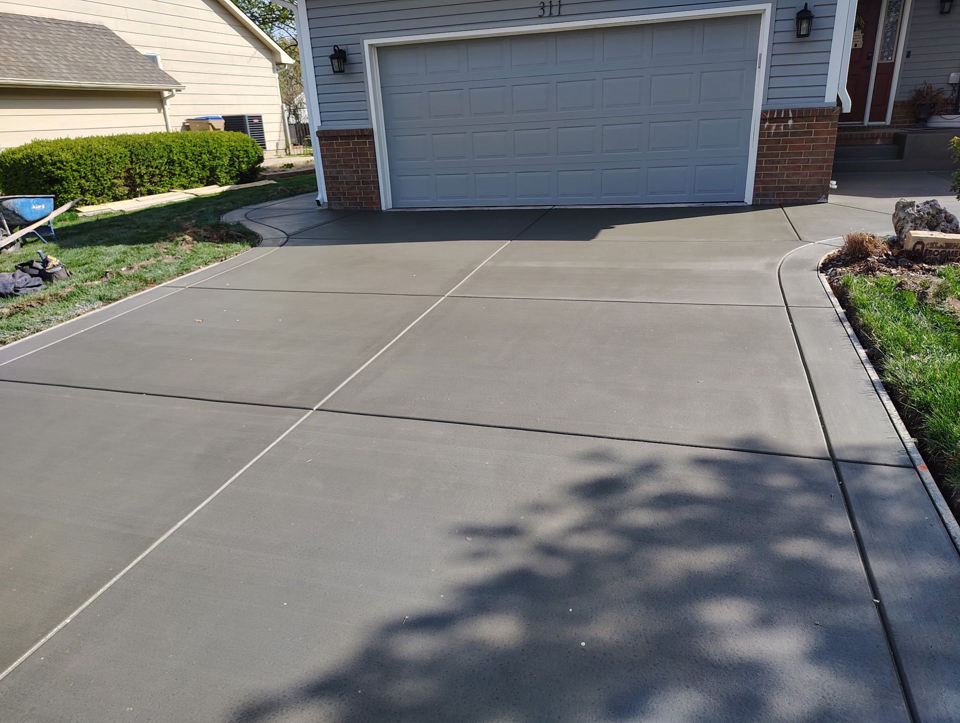 A concrete driveway in front of a house with a garage door.