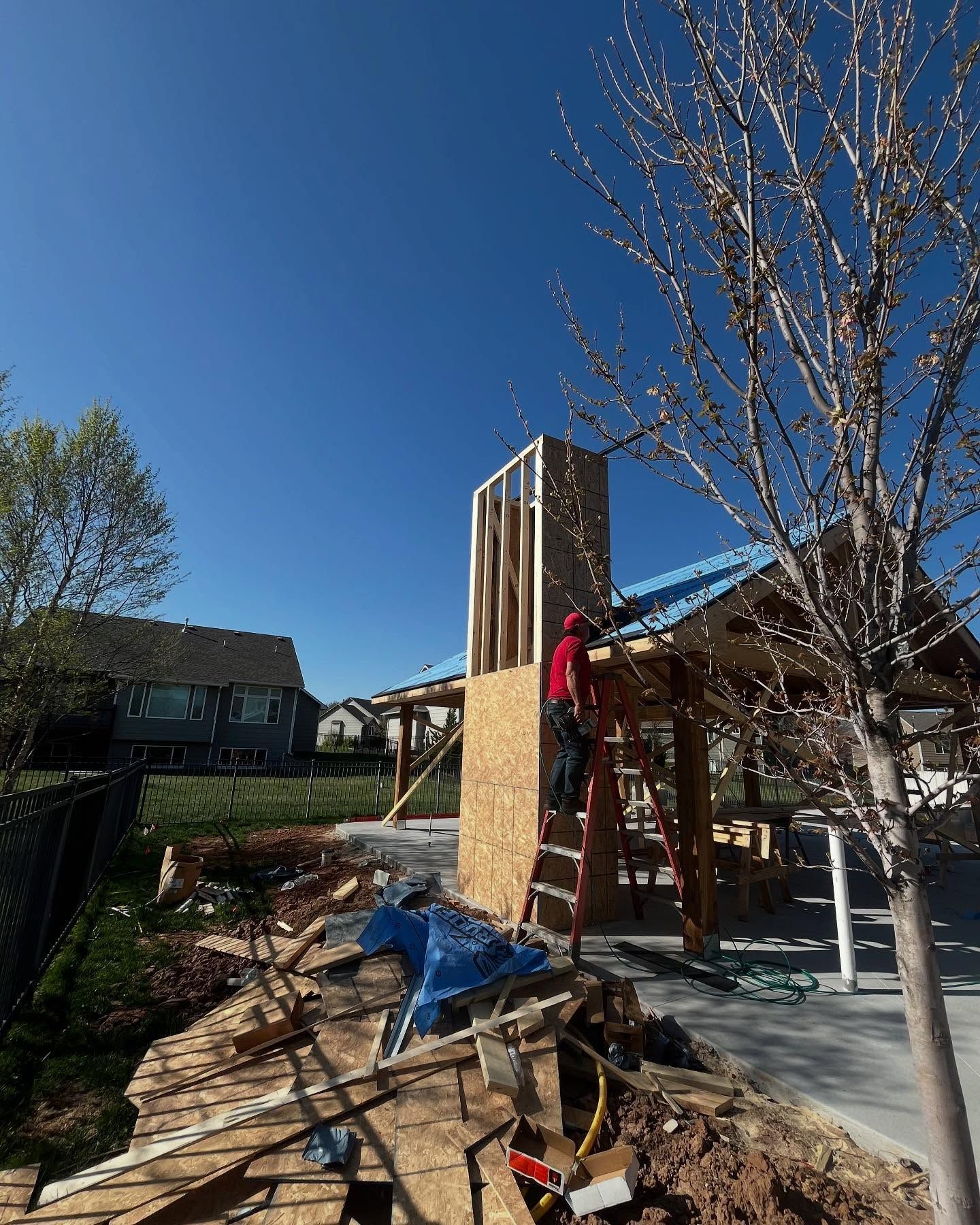A man is standing on a ladder in front of a building under construction.