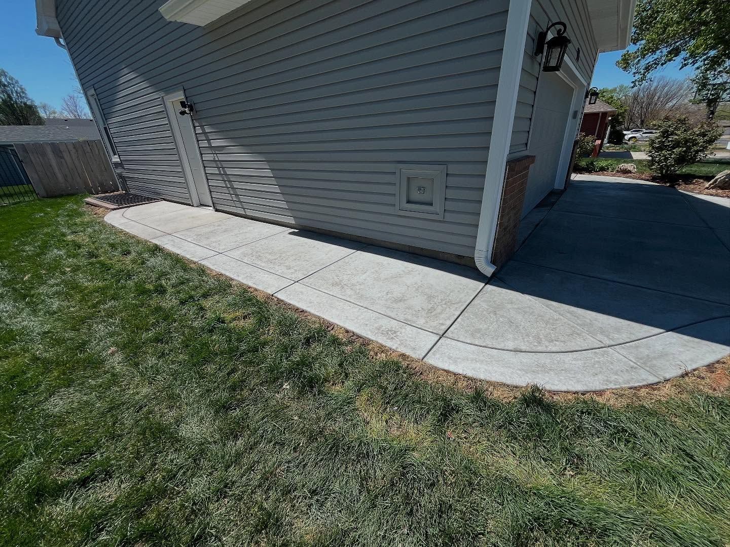 A concrete walkway is leading to the side of a house.