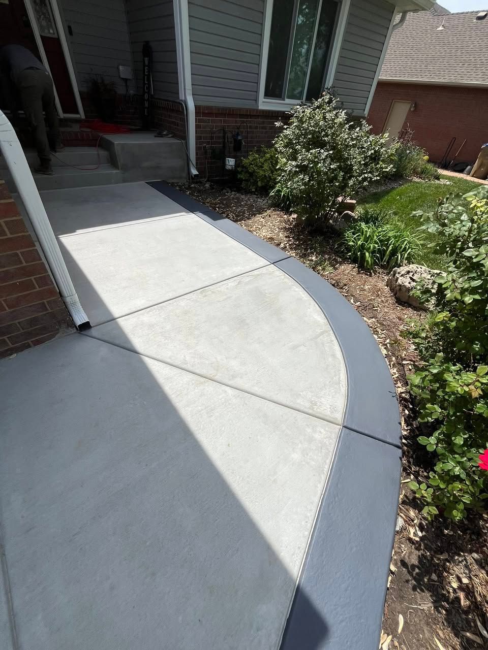 A concrete walkway leading to the front door of a house.