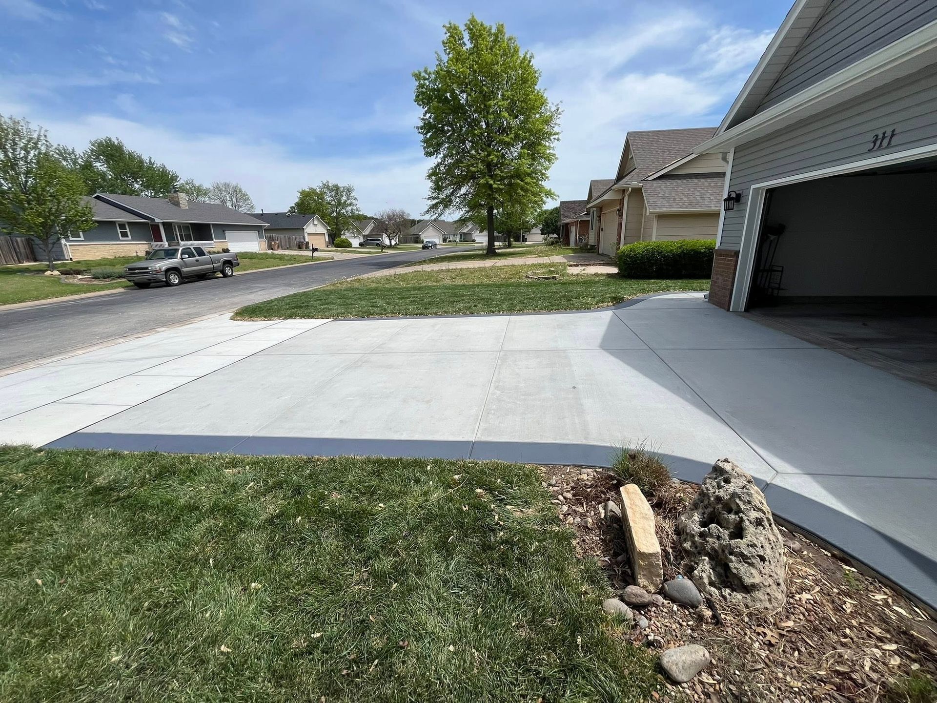 A concrete driveway leading to a garage in a residential neighborhood