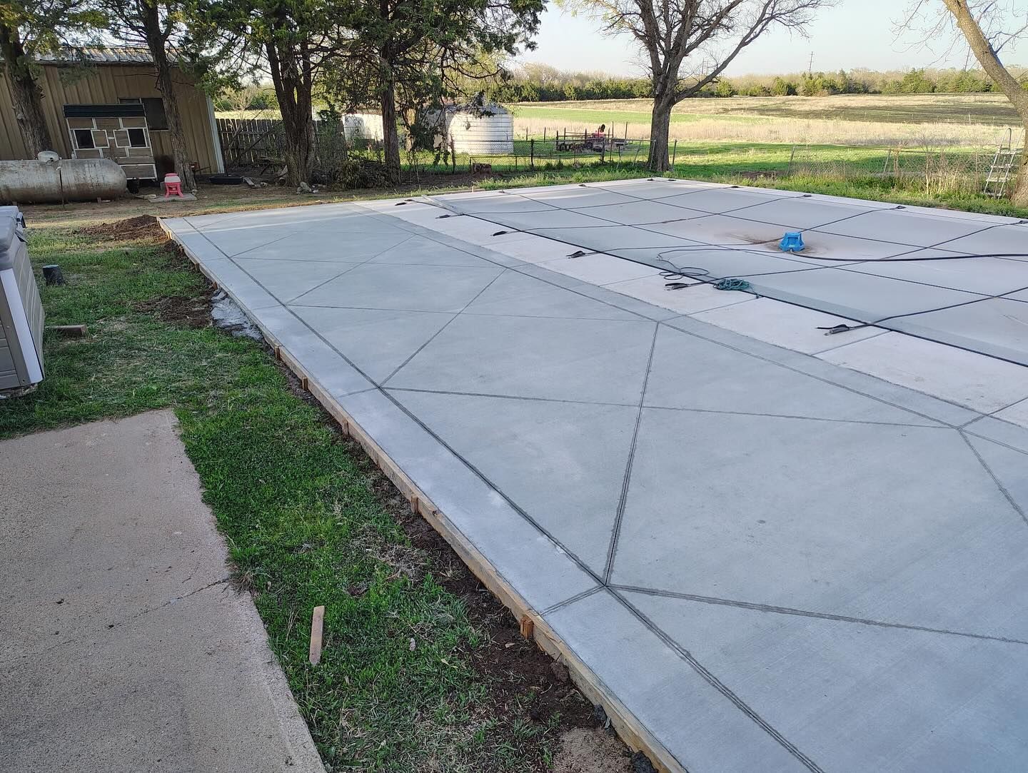 A concrete driveway is being built in the backyard of a house.
