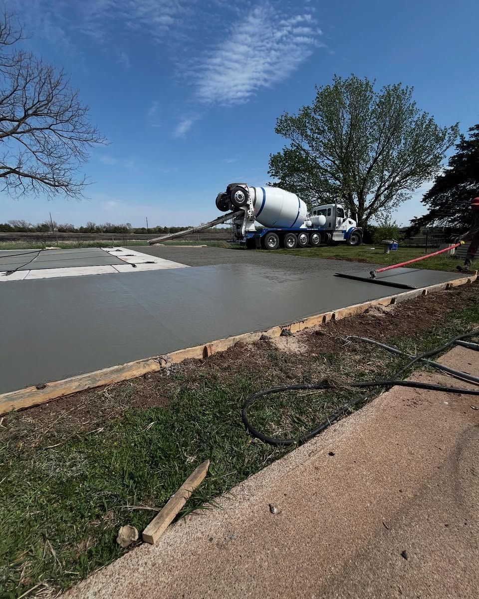 A concrete mixer truck is pouring concrete into a concrete driveway.